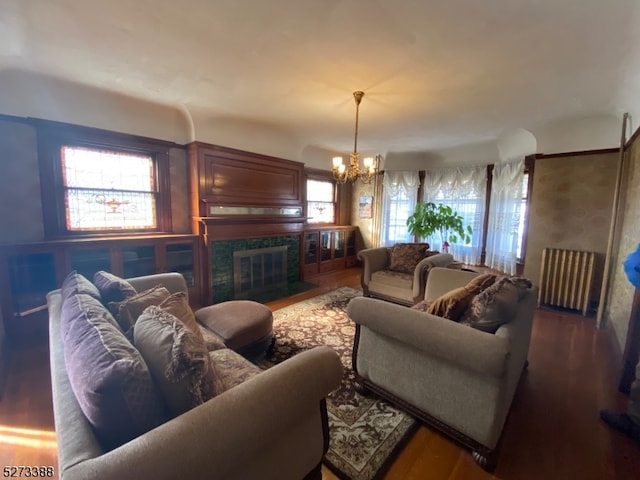 living room with dark wood-type flooring, a fireplace, and a chandelier