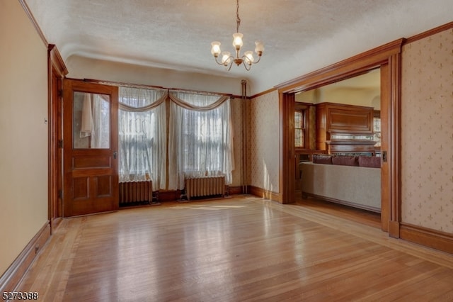 interior space with a chandelier, radiator heating unit, and light wood-type flooring