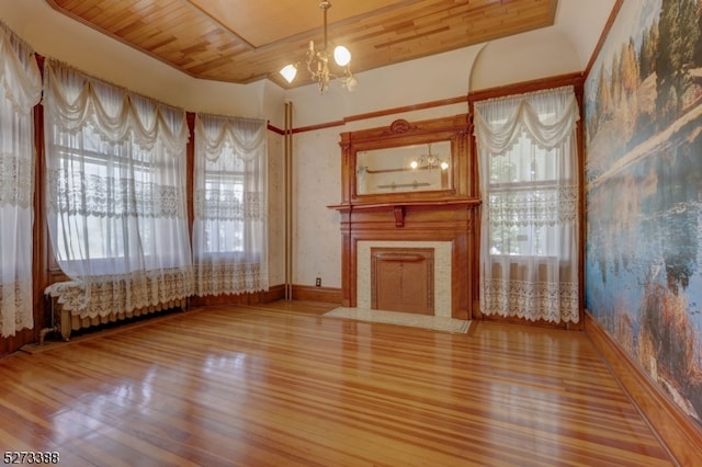 unfurnished living room with an inviting chandelier, light wood-type flooring, wood ceiling, and a healthy amount of sunlight