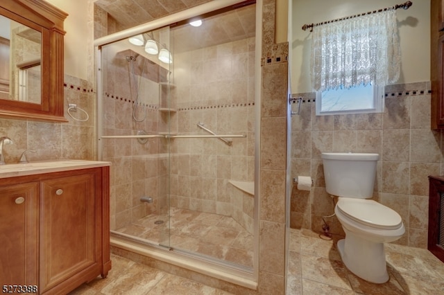 bathroom with toilet, vanity, walk in shower, tile walls, and tile floors