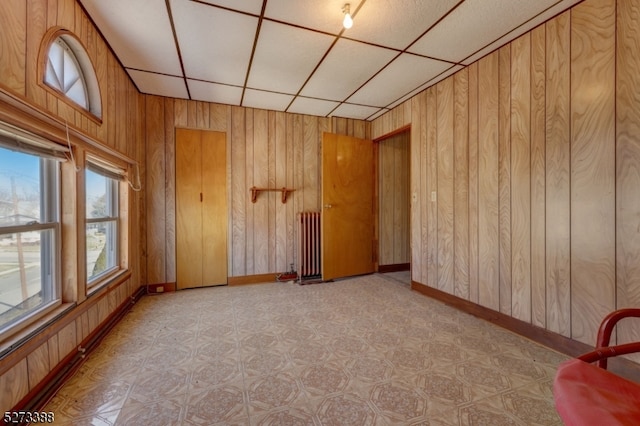 unfurnished room with radiator heating unit and wooden walls