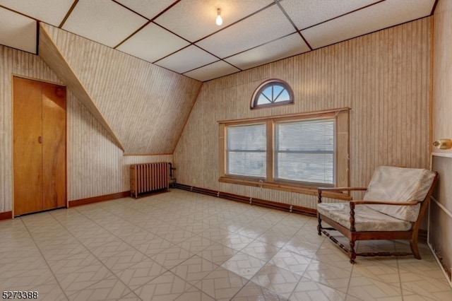 bonus room featuring vaulted ceiling, wood walls, light tile floors, and radiator