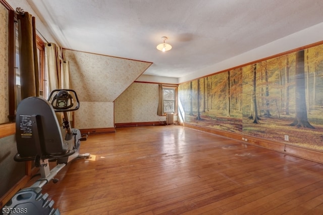 workout area with vaulted ceiling and light wood-type flooring