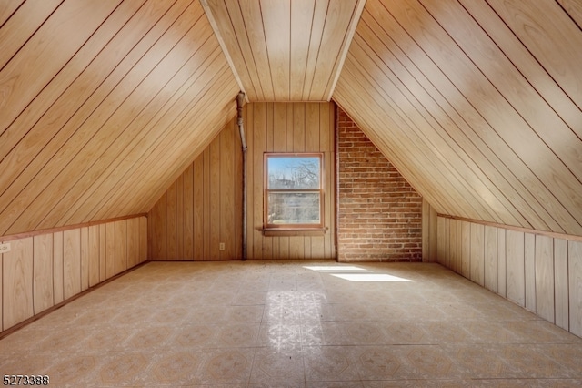 bonus room with lofted ceiling, wooden walls, wooden ceiling, and brick wall