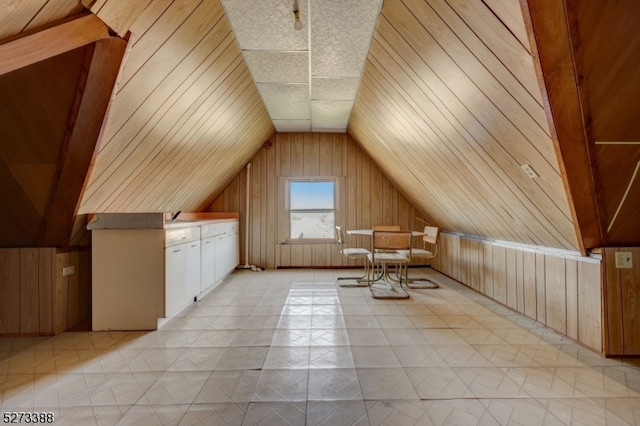 bonus room with wooden walls, vaulted ceiling, light tile floors, and a textured ceiling