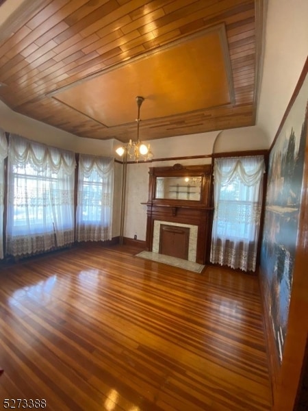 unfurnished living room with wood ceiling, a chandelier, dark hardwood / wood-style floors, and a healthy amount of sunlight