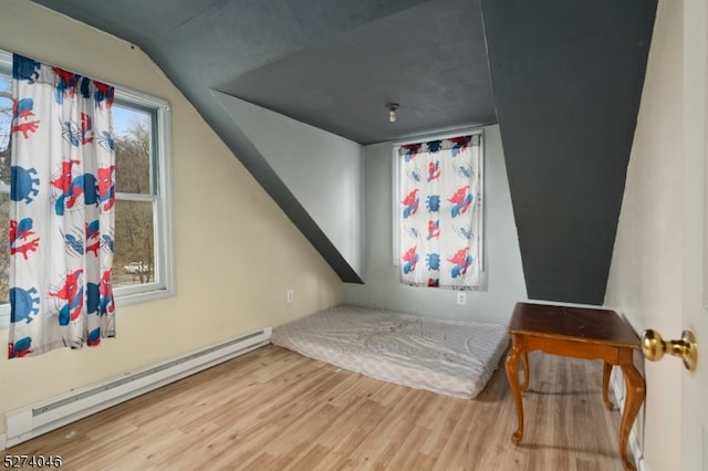 bedroom with lofted ceiling, multiple windows, a baseboard radiator, and light hardwood / wood-style flooring