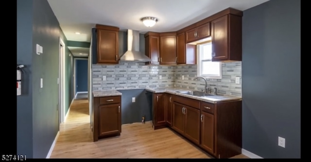 kitchen featuring sink, backsplash, light hardwood / wood-style floors, and wall chimney exhaust hood