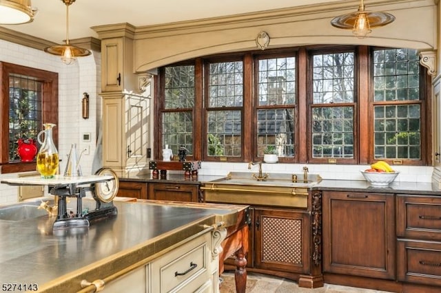 kitchen featuring a sink, hanging light fixtures, stainless steel counters, and decorative backsplash