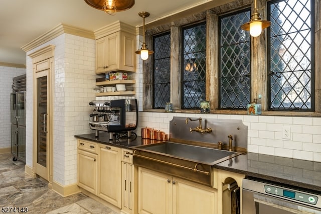 kitchen featuring brick wall, backsplash, hanging light fixtures, ornamental molding, and sink