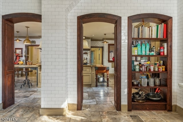 corridor with crown molding and brick wall