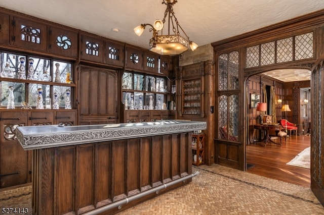 bar featuring hardwood / wood-style flooring, a textured ceiling, and dark brown cabinets