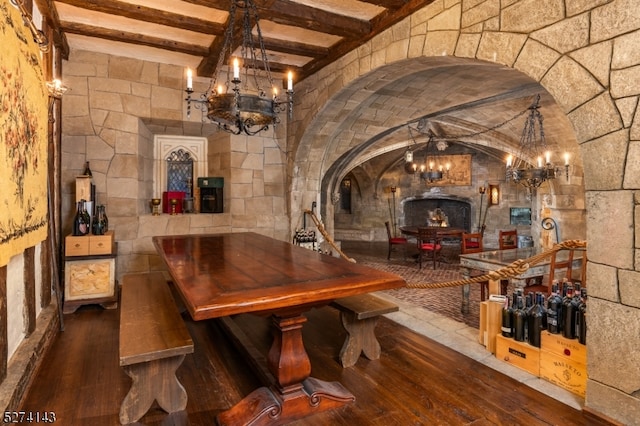 wine cellar with wood-type flooring, a chandelier, and beamed ceiling