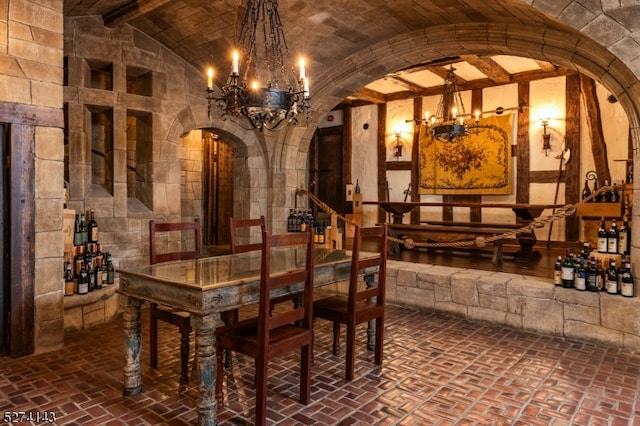 wine room featuring an inviting chandelier and vaulted ceiling