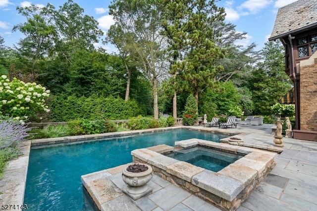 outdoor pool with a patio area and an in ground hot tub