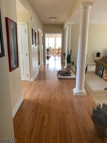 corridor featuring hardwood / wood-style flooring and decorative columns