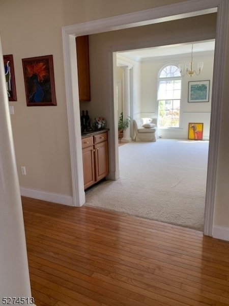 hallway with an inviting chandelier and hardwood / wood-style floors