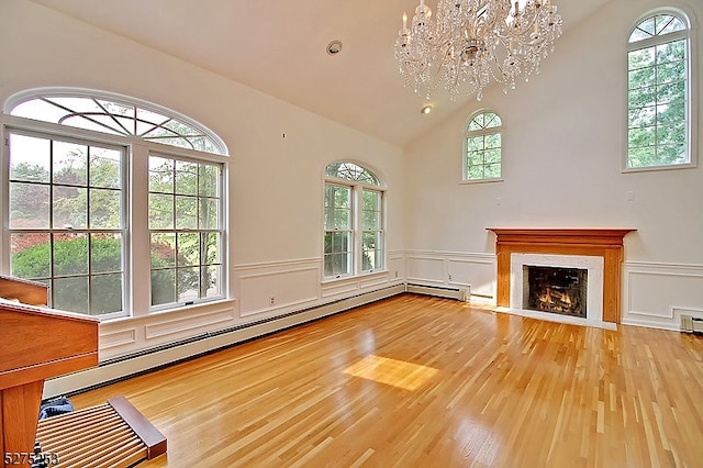 unfurnished living room featuring an inviting chandelier, a high end fireplace, a wealth of natural light, and light hardwood / wood-style floors