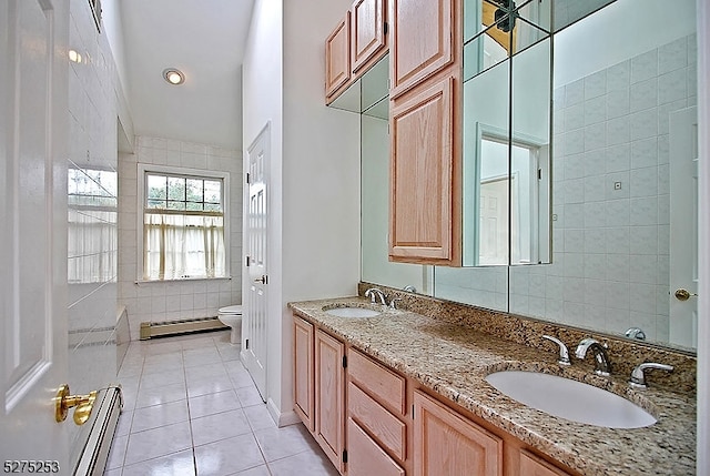 bathroom with dual sinks, tile flooring, toilet, vanity with extensive cabinet space, and tile walls