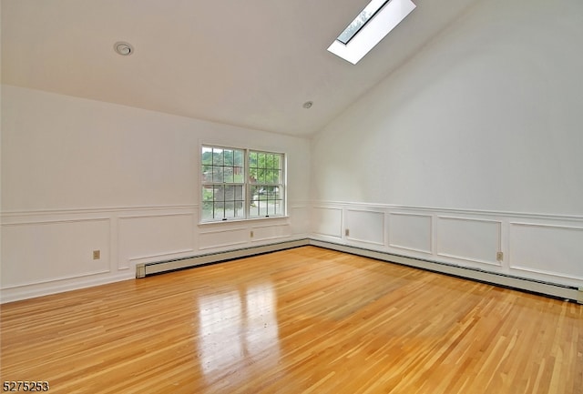 unfurnished room with light hardwood / wood-style flooring, baseboard heating, and vaulted ceiling with skylight