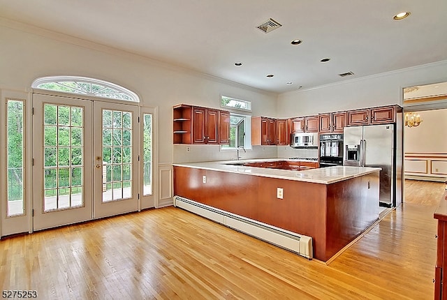 kitchen featuring a healthy amount of sunlight, an inviting chandelier, a baseboard radiator, light wood-type flooring, and stainless steel appliances