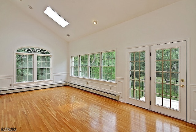 spare room with a skylight, a baseboard radiator, plenty of natural light, and light hardwood / wood-style floors