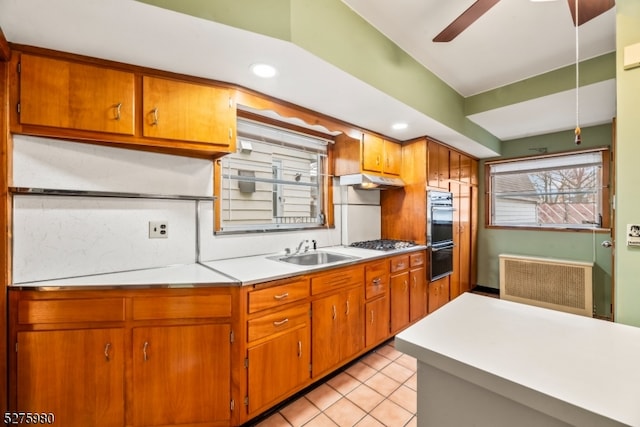 kitchen with light tile flooring, stainless steel gas cooktop, ceiling fan, sink, and radiator heating unit