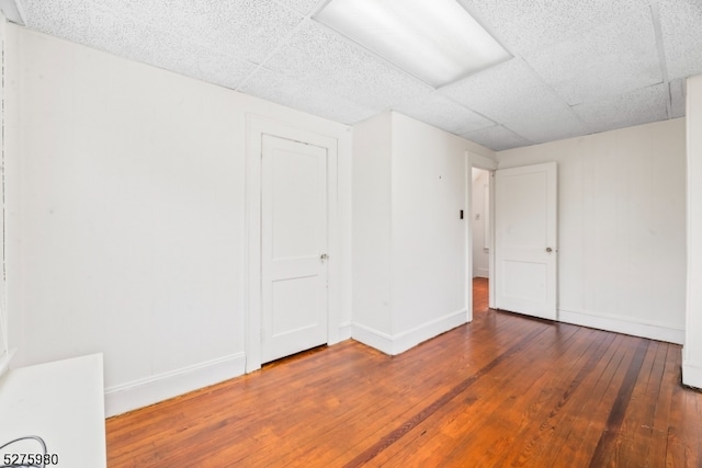 spare room featuring dark hardwood / wood-style flooring and a drop ceiling