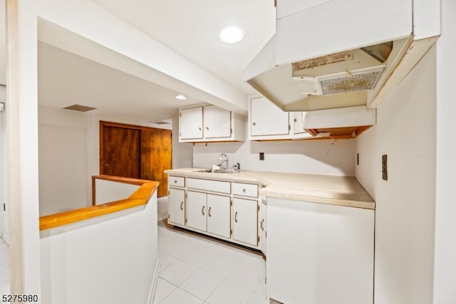 kitchen with light tile flooring, white cabinets, and sink