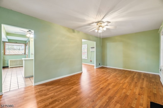 empty room with radiator heating unit, ceiling fan, and light wood-type flooring