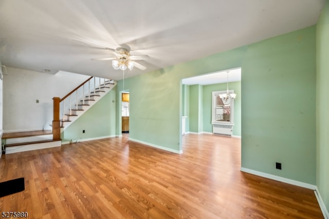 interior space featuring radiator, ceiling fan with notable chandelier, and light wood-type flooring