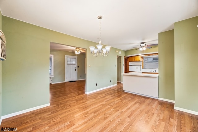 unfurnished living room featuring light hardwood / wood-style flooring and ceiling fan with notable chandelier