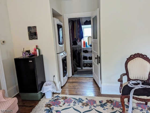 bedroom with dark hardwood / wood-style flooring, a closet, and stacked washer / drying machine