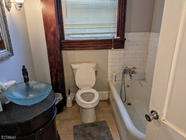 bathroom with tile flooring, vanity with extensive cabinet space, a tub, and toilet