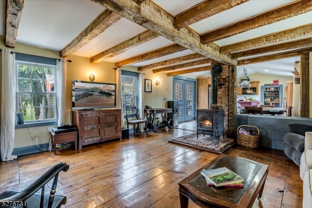 living room with a wood stove, beam ceiling, and dark wood-type flooring