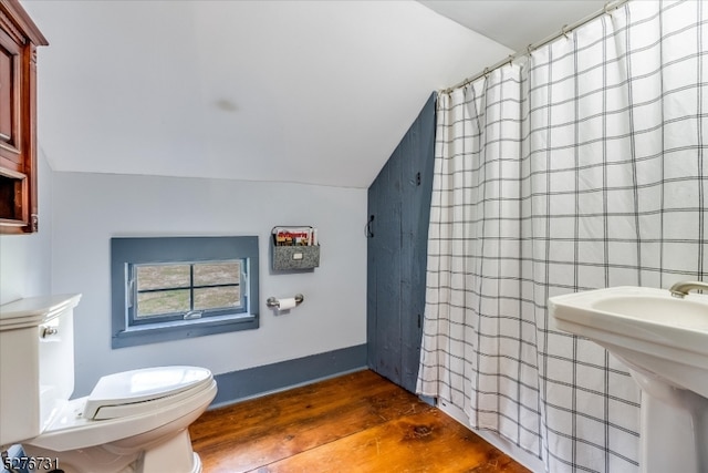 bathroom with tile walls, toilet, sink, wood-type flooring, and vaulted ceiling