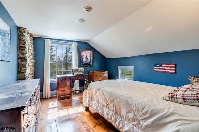 bedroom with lofted ceiling and multiple windows