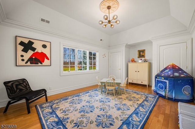 sitting room featuring a notable chandelier, ornamental molding, a tray ceiling, and hardwood / wood-style flooring