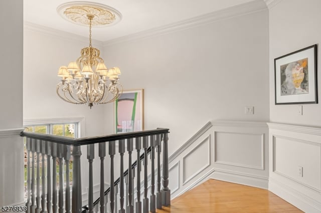 hall with a notable chandelier, light hardwood / wood-style flooring, and crown molding