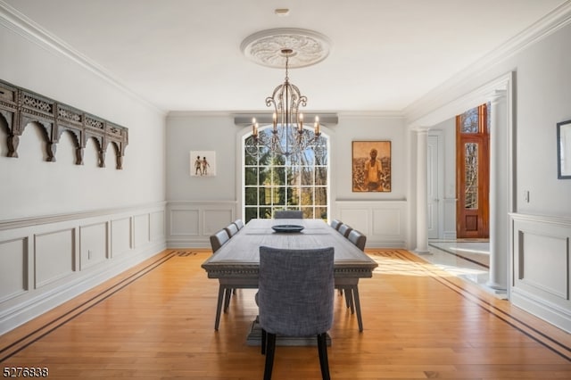 dining area with light hardwood / wood-style floors, crown molding, and an inviting chandelier