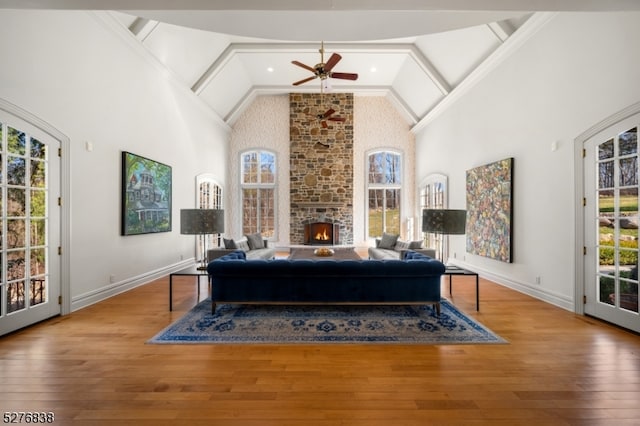 living room with a stone fireplace, high vaulted ceiling, hardwood / wood-style flooring, and ceiling fan