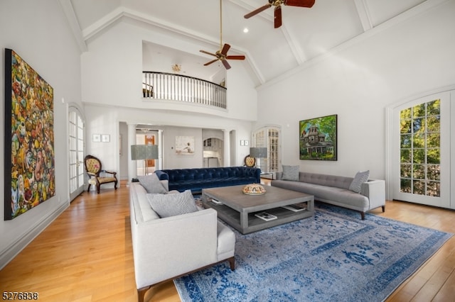 living room featuring light wood-type flooring, high vaulted ceiling, ceiling fan, and beamed ceiling