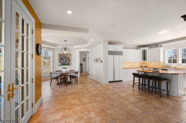 kitchen with backsplash, white cabinetry, a breakfast bar area, and a wealth of natural light