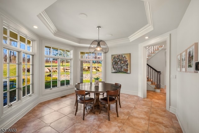 dining room featuring a raised ceiling, an inviting chandelier, light tile flooring, and ornamental molding