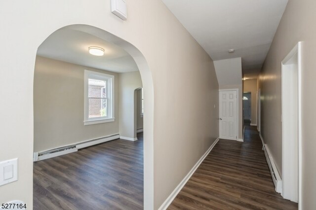 corridor with a baseboard heating unit and dark wood-type flooring