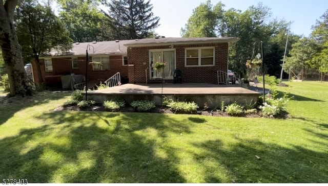 rear view of property featuring a wooden deck and a lawn