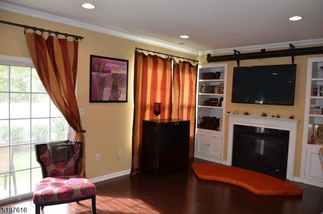 living room featuring baseboards, a glass covered fireplace, wood finished floors, crown molding, and recessed lighting