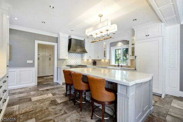 kitchen featuring a kitchen island, custom exhaust hood, white cabinets, and a kitchen bar