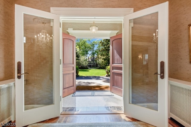 doorway to outside with french doors, a notable chandelier, and radiator heating unit