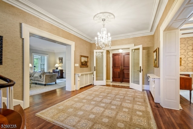 foyer featuring wood-type flooring, french doors, a notable chandelier, and crown molding